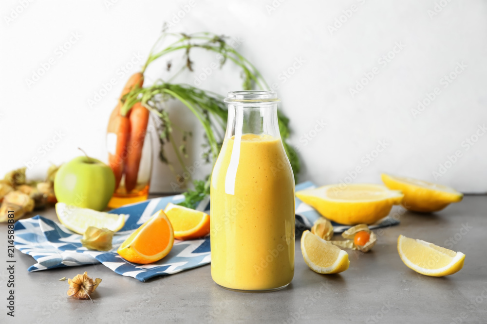 Bottle of fresh tasty smoothie and ingredients on table