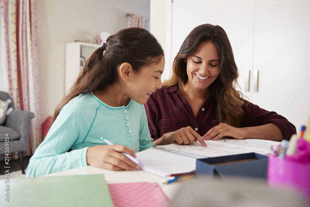 Mother Helping Daughter With Homework Sitting At Desk In Bedroom Mother Helping Daughter With Homework Sitting At Desk In Bedroom