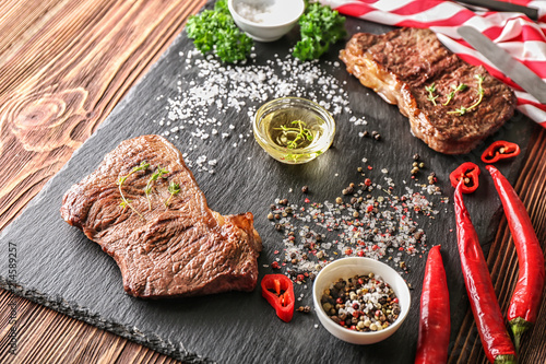 Tasty grilled meat with oil and spices on slate plate