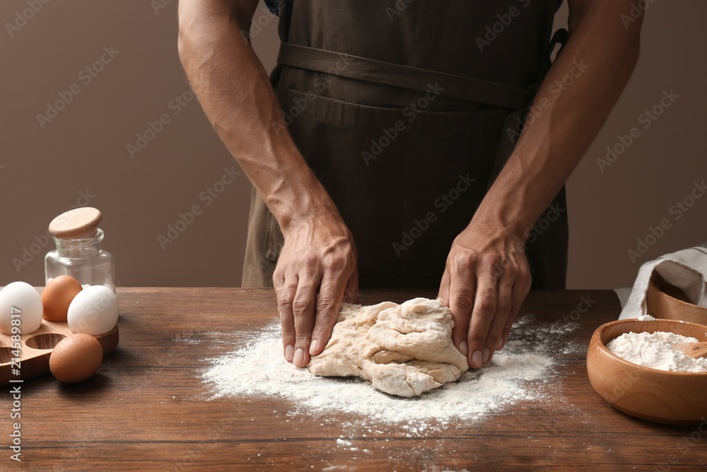 Man kneading dough on wooden table