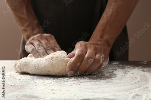 Fototapeta Naklejka Na Ścianę i Meble -  Man kneading dough on wooden table