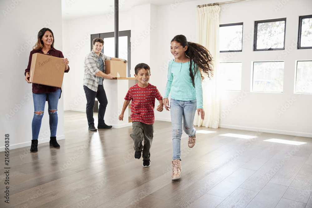 Excited Family Carrying Boxes Into New Home On Moving Day Excited Family Carrying Boxes Into New Home On Moving Day