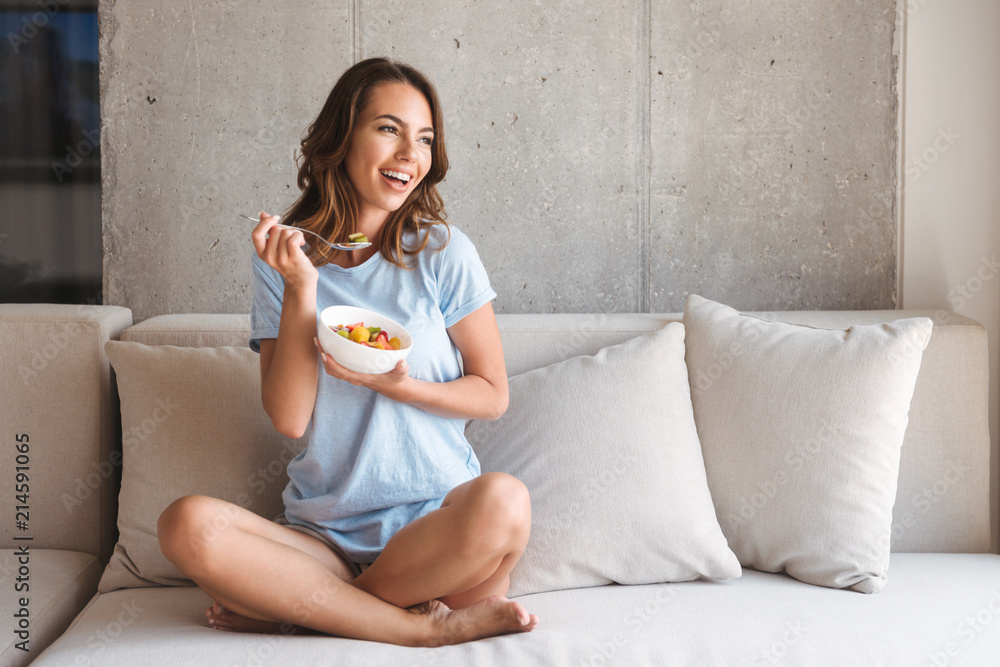 Happy young woman eating healthy breakfast - obrazy, fototapety, plakaty 