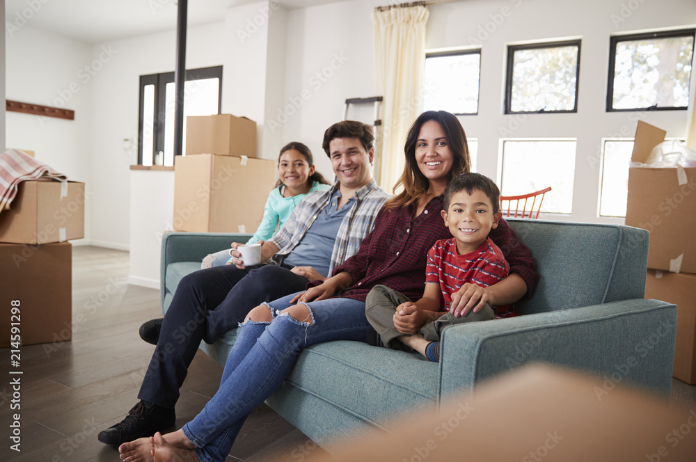 Portrait Of Happy Family Resting On Sofa Surrounded By Boxes In New Home On Moving Day Portrait Of Happy Family Resting On Sofa Surrounded By Boxes In New Home On Moving Day