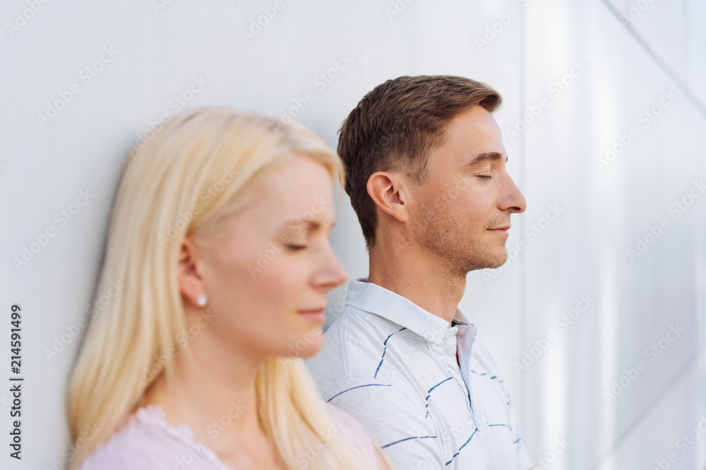 Young couple standing meditating with closed eyes