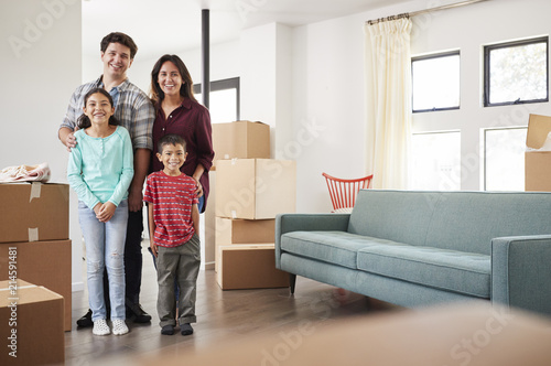 Portrait Of Happy Family Surrounded By Boxes In New Home On Moving Day