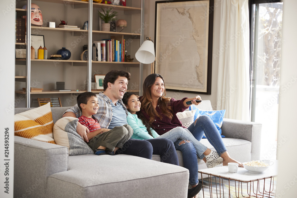 Obraz premium Family Relaxing On Sofa At Home Watching Television