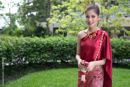 Asian girl wearing thai traditional dress and holding flowers. Horizontal