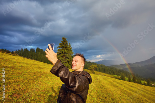 young guy  a tourist  makes a selfie on a rainbow