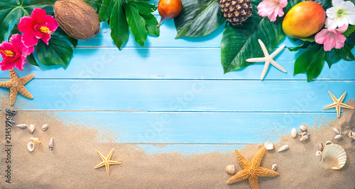 Holidays background with tropical flowers, leaves, exotic fruits and seashells on sand beach photo