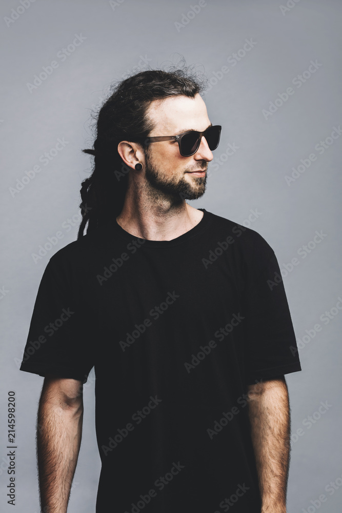 Young man in sunglasses and black t-shirt on a grey background. Young man in sunglasses and black t-shirt on a grey background.