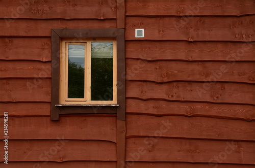 The wall of a wooden farmhouse with a window. Background. Texture.