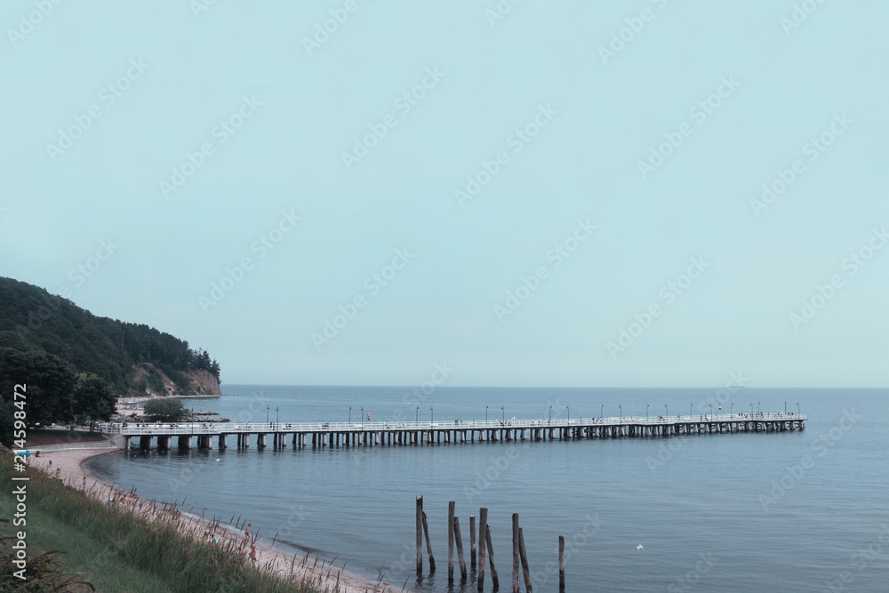 Pier on the beach, with a clear sky and calm sea with sandy beach. Photo of an amazing nature