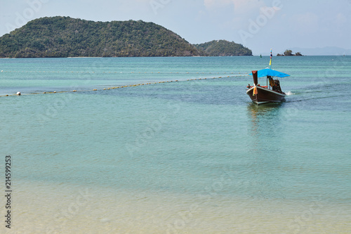 Long tail boat at the beach with blue sea with the island background