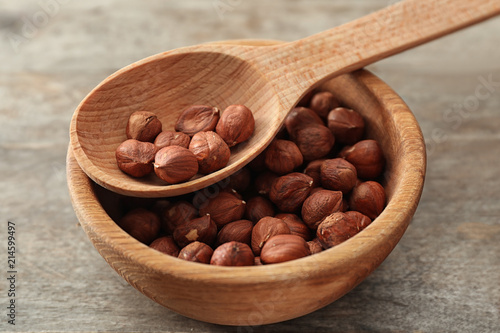 Bowl and spoon with fresh tasty hazelnuts on wooden table