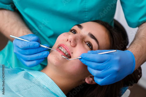 Dentist hands working on young teen patient with dental braces.
