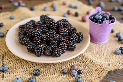 Fresh berries of blueberry, blackberry and gooseberry on a plate. It can be used as a background