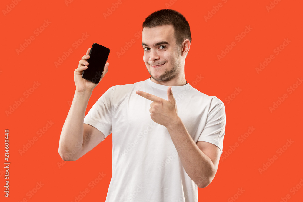 The happy man showing at empty screen of mobile phone against orange background. The happy man showing at empty screen of mobile phone against orange background.
