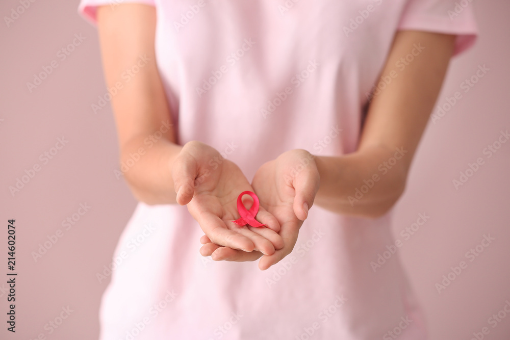 Beautiful woman holding pink ribbon on color background, closeup. Breast cancer concept Beautiful woman holding pink ribbon on color background, closeup. Breast cancer concept