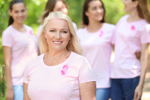 Beautiful mature woman with pink ribbon outdoors. Breast cancer concept