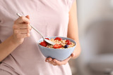 Young woman with bowl of tasty oatmeal, closeup