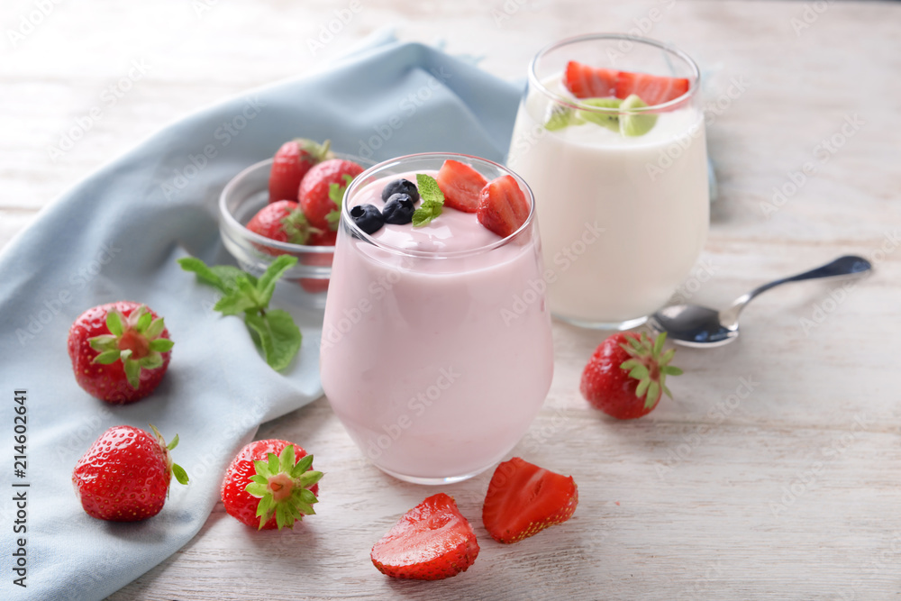 Glasses with yogurt and berries on wooden table Glasses with yogurt and berries on wooden table