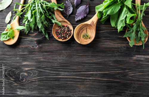 Wooden spoons with fresh herbs and spices on wooden table