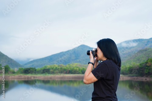 Young traveler woman backpacker use camera take a photo of beautiful of natural lake and mountain view,Freedom wanderlust concept.