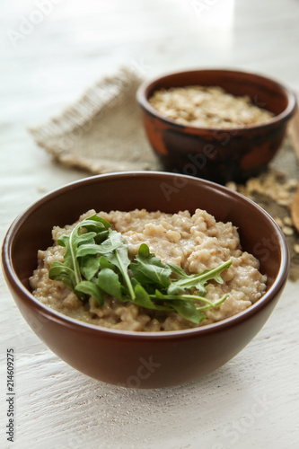 Bowl with tasty oatmeal and arugula on wooden table