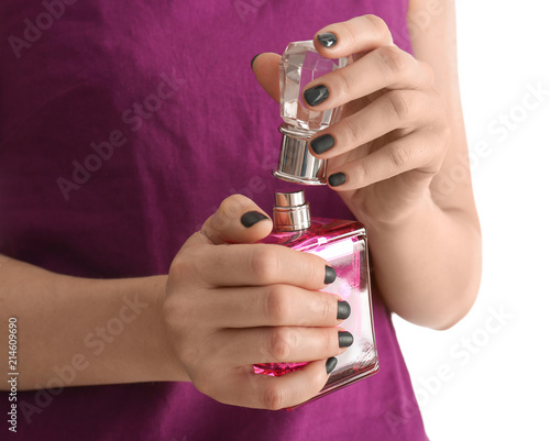 Young woman with beautiful manicure holding bottle of perfume on white background, closeup