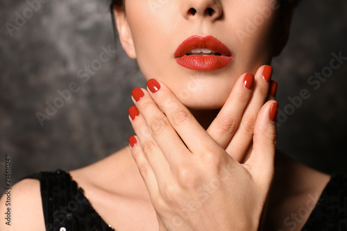 Young woman with beautiful manicure on dark background, closeup