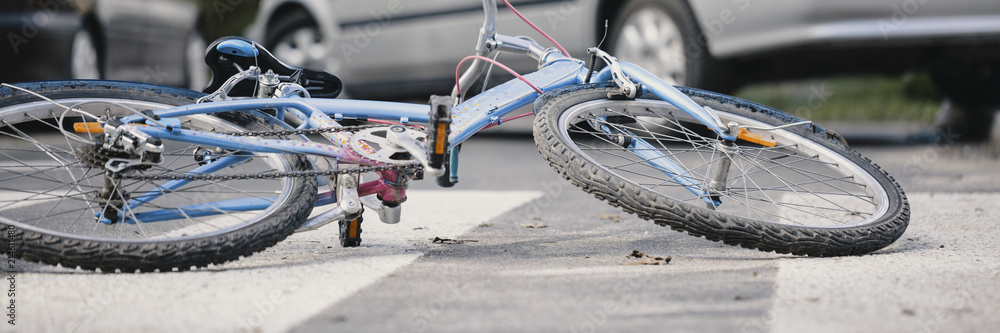 Naklejka premium Zbliżenie rower na pustym skrzyżowaniu drogowym z samochodami w tle - koncepcja niebezpiecznego wypadku samochodowego
