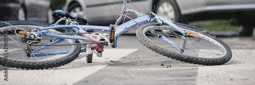 Close-up of a bicycle on an empty road crossing with cars in the background - a dangerous car accident concept