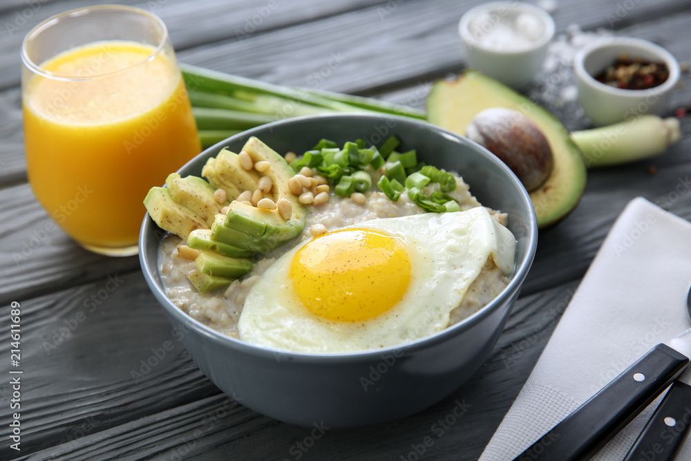 Bowl with delicious oatmeal, egg and avocado on wooden table Bowl with delicious oatmeal, egg and avocado on wooden table