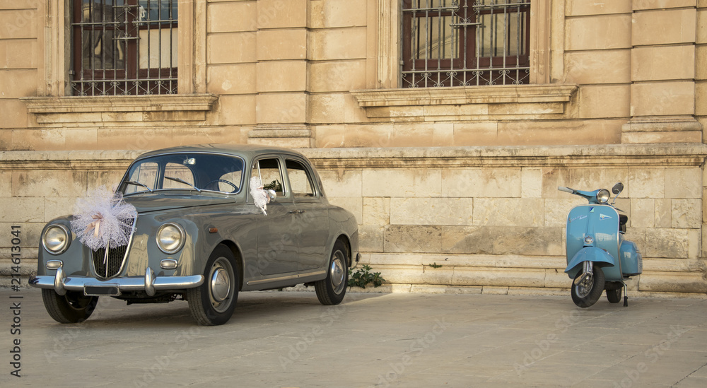 Vespa and classic Lancia wedding car on a square in Sicily, Italy. Typical Italian scene