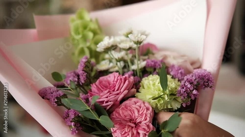 woman florist making bouquet of pink flowers indoor. Female florist preparing bouquet of roses and carnation in flower shop. entrepreneurship, small business, workplace concept. Close up