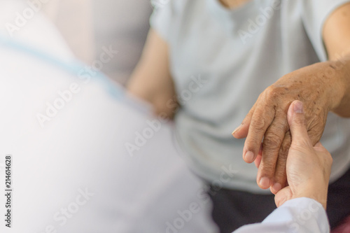 Parkinson and alzheimer female senior elderly patient hand with physician doctor exam in hospice care room. photo
