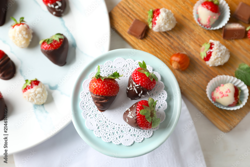 Dessert stand with delicious strawberries dipped in dark chocolate on light table Dessert stand with delicious strawberries dipped in dark chocolate on light table