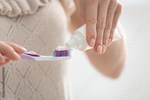 Young woman squeezing toothpaste on brush, closeup