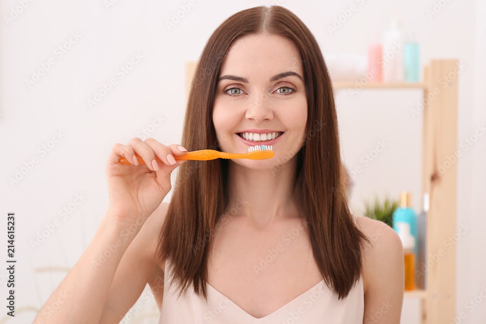 Young woman brushing her teeth in bathroom Young woman brushing her teeth in bathroom