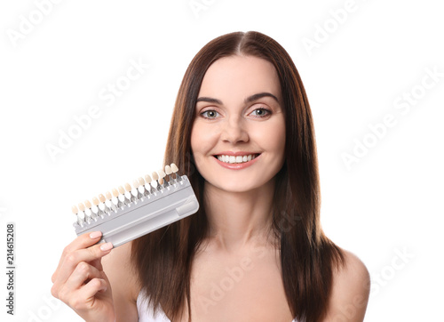 Beautiful young woman with teeth color samples on white background