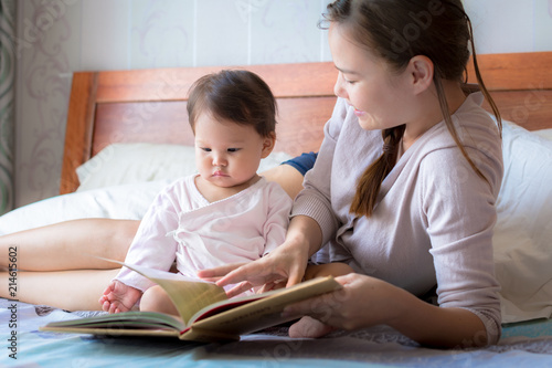 Mother reading a book to her child on the bed.  Bedtime story. Learning how to read.