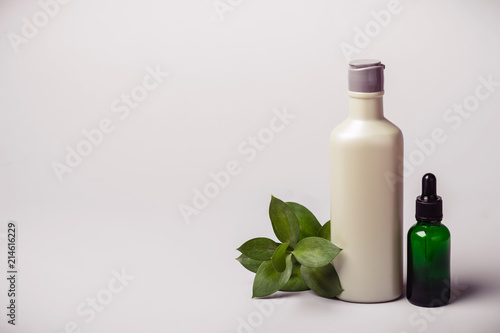 Bottle with cosmetic product, essence oil and green twig