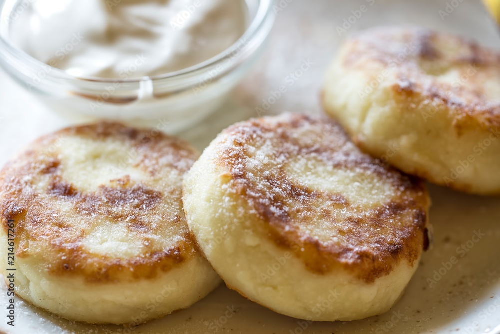 Tasty cheese pancakes on a plate with sour cream Tasty cheese pancakes on a plate with sour cream