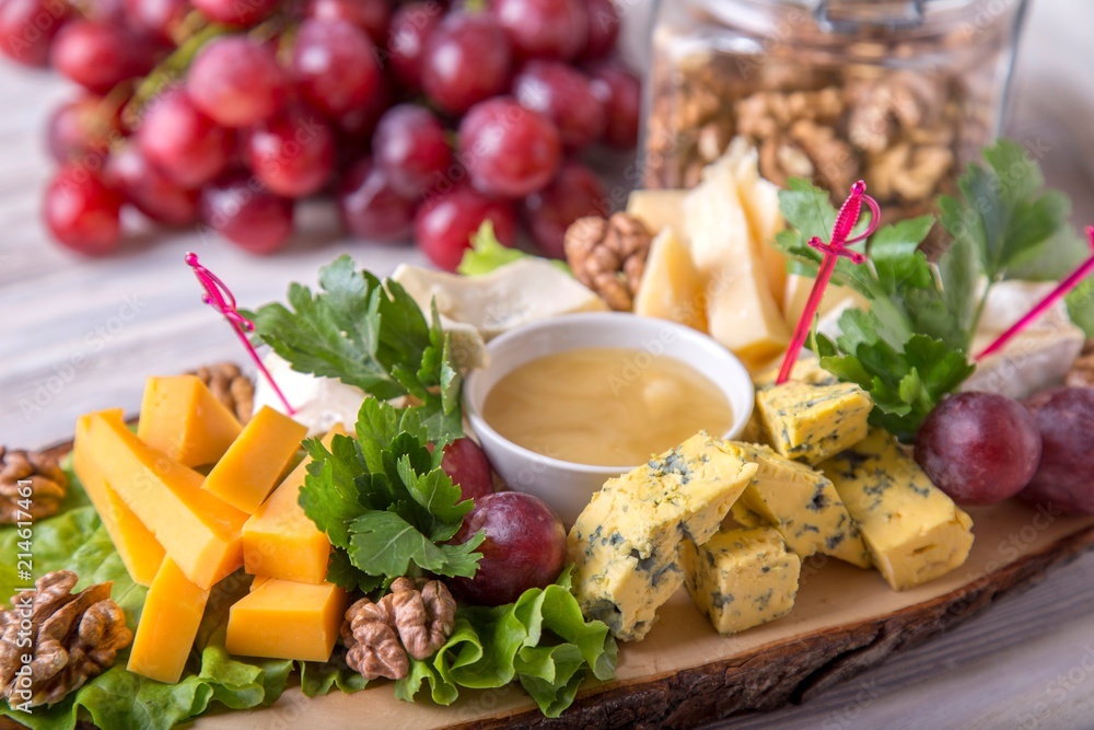 Cheese plate served with nuts and honey on wooden board Cheese plate served with nuts and honey on wooden board
