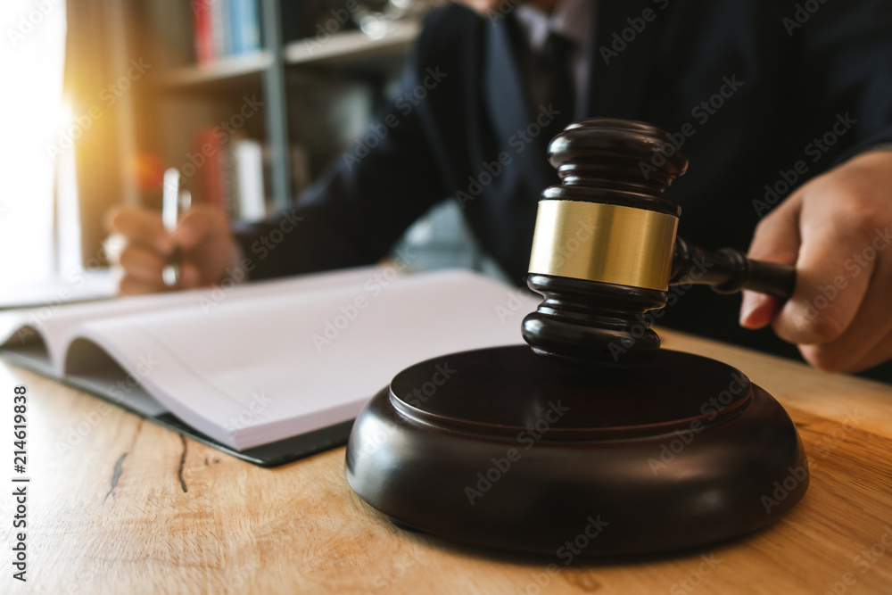 Justice and law concept.Male judge in a courtroom with the gavel,working with,digital tablet computer docking keyboard,eyeglasses,on wood table Justice and law concept.Male judge in a courtroom with the gavel,working with,digital tablet computer docking keyboard,eyeglasses,on wood table