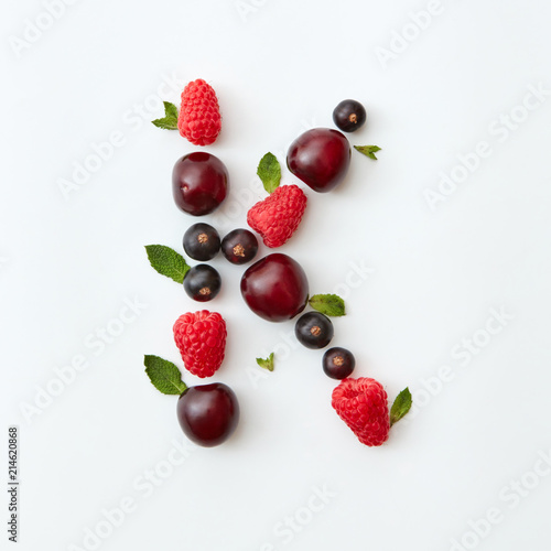 Fototapeta Naklejka Na Ścianę i Meble -  Summer pattern of letter K english alphabet from natural ripe berries - black currant, cherries, raspberry, mint leaf isolated on a white background.