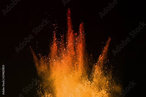 orange powder explosion isolated on black background. Freeze motion of colored dust splatted.