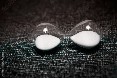Fotografija hourglass with white sand on dark background