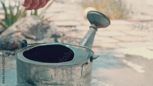 Filling a watering can and taking it into the garden to water the plants. photo